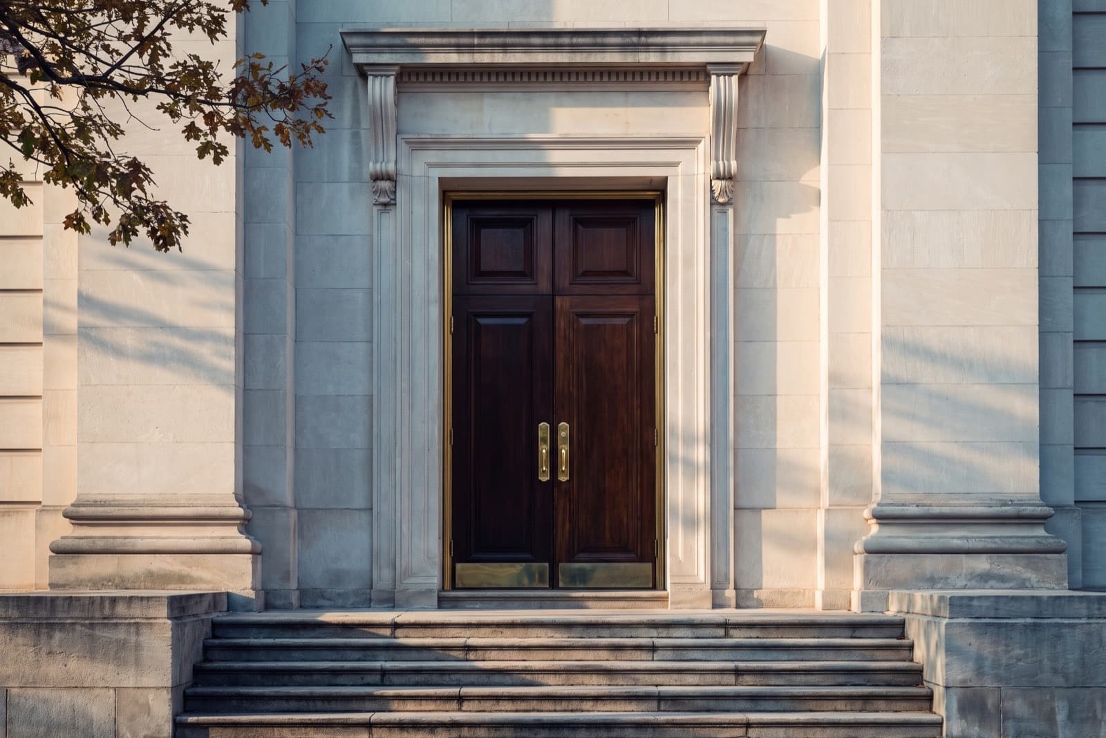 Entrance of the Roots Global office building, dark wooden doors with brass frames in a limestone facade